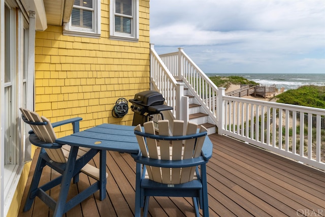 balcony with a beach view, grilling area, and a water view