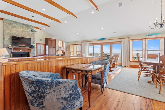 dining room featuring lofted ceiling with beams, light wood-style flooring, a fireplace, a chandelier, and recessed lighting