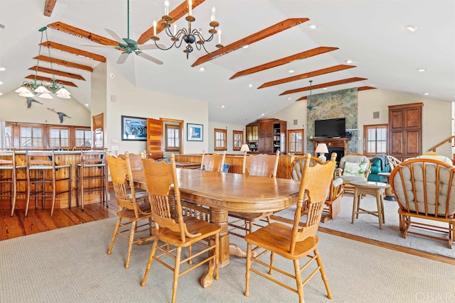 dining space with a large fireplace, light wood finished floors, beamed ceiling, and plenty of natural light