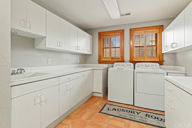 laundry room featuring cabinet space, light tile patterned floors, visible vents, separate washer and dryer, and a sink