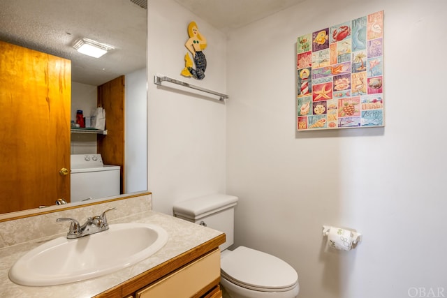 bathroom featuring toilet, vanity, and washer / dryer