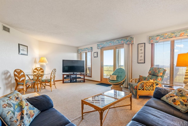 living room with carpet floors, visible vents, a textured ceiling, and baseboards