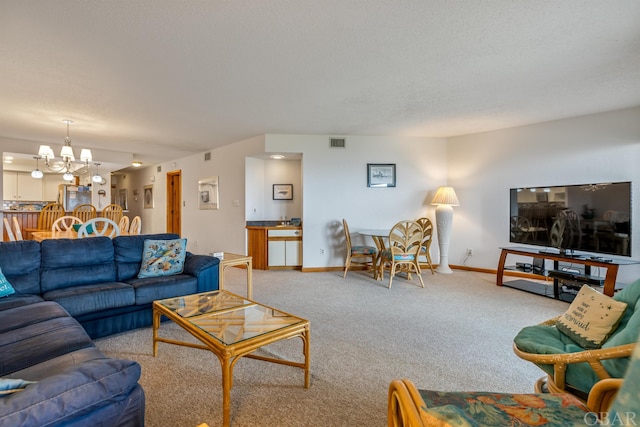 living area with baseboards, a textured ceiling, carpet, and a notable chandelier