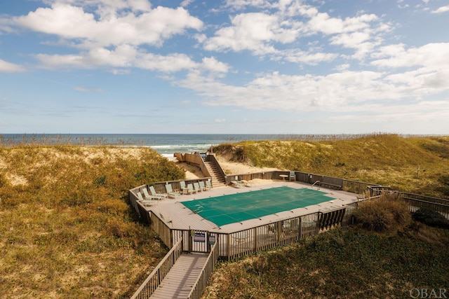 pool featuring a patio area, a water view, fence, and stairs