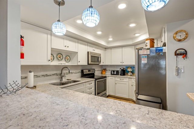 kitchen with a sink, white cabinets, hanging light fixtures, appliances with stainless steel finishes, and a raised ceiling