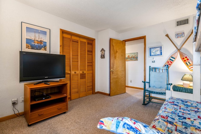 carpeted bedroom featuring baseboards, a textured ceiling, visible vents, and a closet