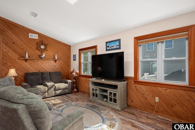 living area featuring a wainscoted wall, visible vents, wooden walls, and wood finished floors