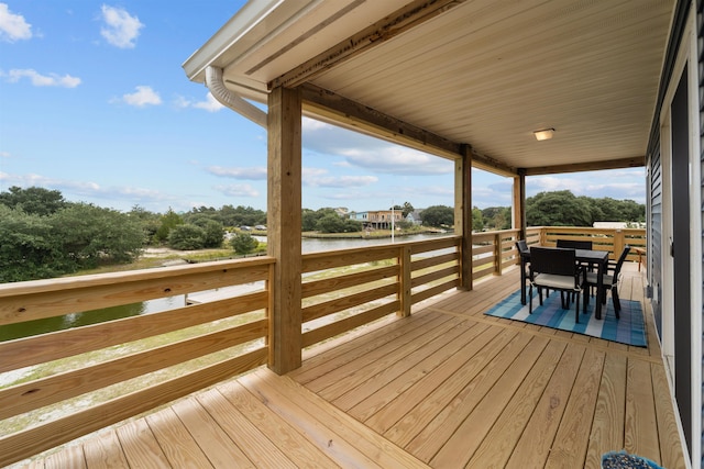 wooden terrace featuring outdoor dining space and a water view