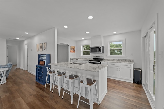 kitchen with appliances with stainless steel finishes, a breakfast bar, dark wood-style flooring, and white cabinets