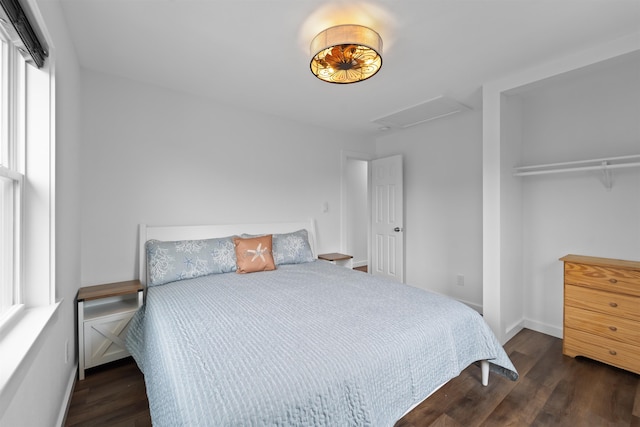 bedroom featuring attic access, baseboards, and wood finished floors