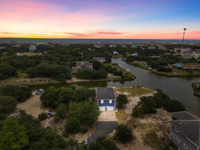 aerial view at dusk featuring a water view