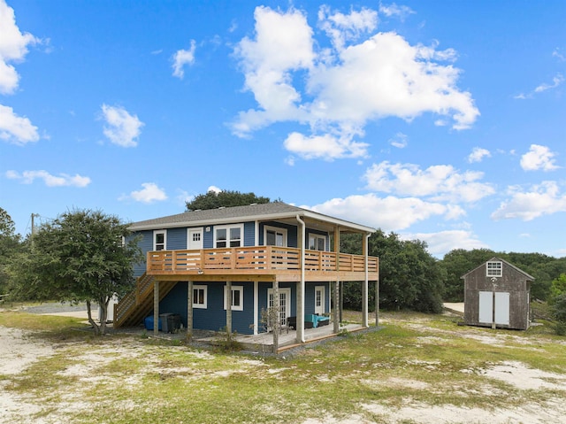 rear view of property with a storage shed, a patio, stairway, an outbuilding, and a wooden deck