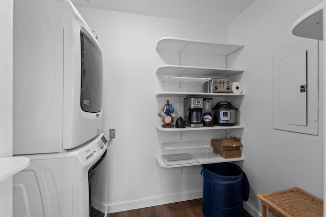 laundry area with laundry area, stacked washer / dryer, baseboards, electric panel, and dark wood-style floors