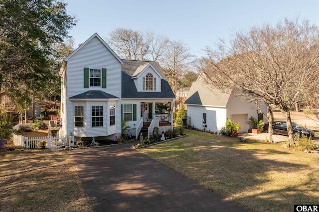 view of front of house featuring covered porch, a shingled roof, fence, and a front lawn