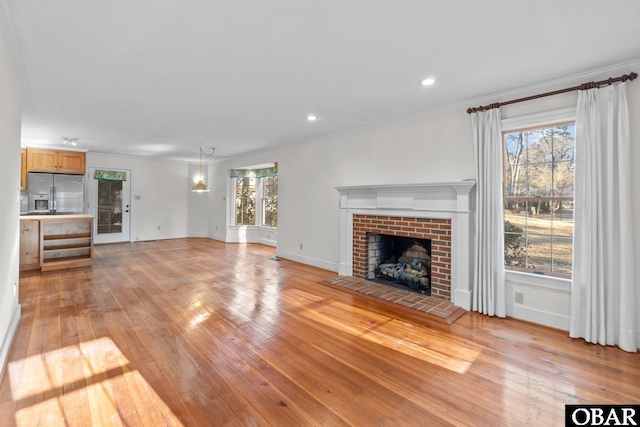 unfurnished living room featuring a brick fireplace, baseboards, light wood-style floors, and recessed lighting