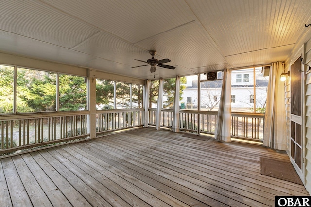 unfurnished sunroom with a healthy amount of sunlight, a water view, and a ceiling fan