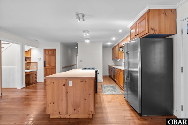 kitchen featuring stainless steel appliances, light wood-type flooring, a kitchen island, and ornamental molding