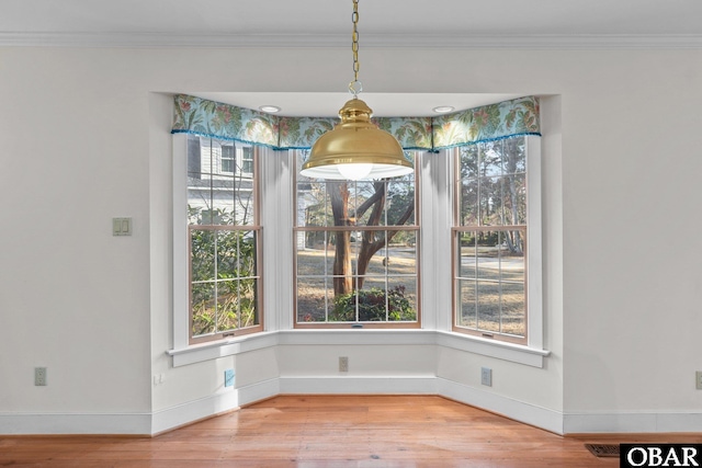 unfurnished dining area with baseboards, wood finished floors, visible vents, and crown molding