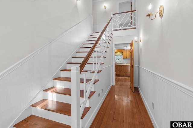 staircase with a wainscoted wall and hardwood / wood-style floors