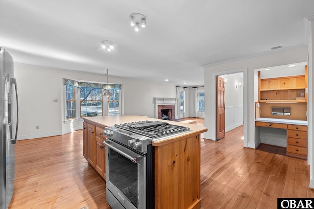 kitchen featuring light wood-style floors, stainless steel appliances, built in desk, and light countertops