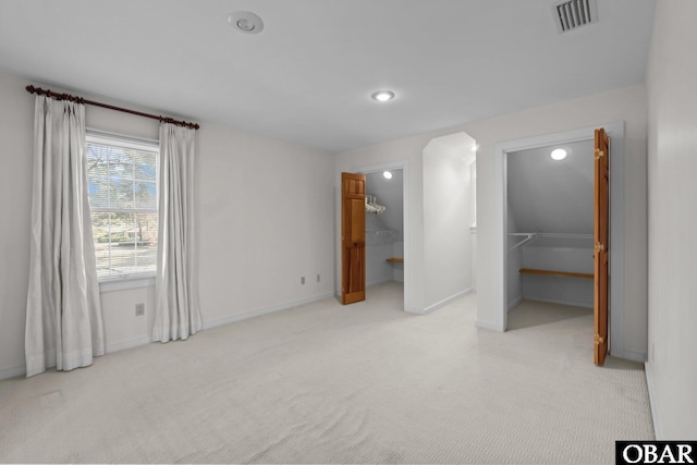 unfurnished bedroom with carpet floors, a closet, visible vents, a spacious closet, and baseboards