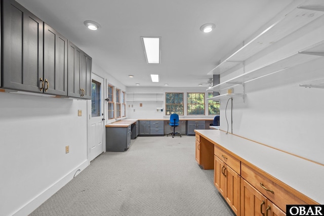 kitchen featuring recessed lighting, light colored carpet, baseboards, light countertops, and built in study area