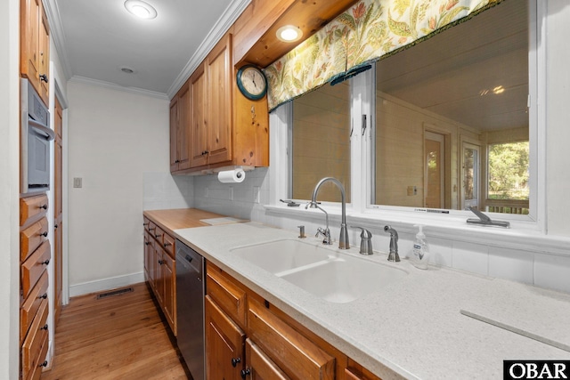 kitchen featuring appliances with stainless steel finishes, a sink, visible vents, and brown cabinets