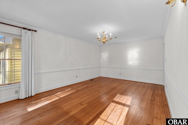 unfurnished room featuring ornamental molding, a healthy amount of sunlight, hardwood / wood-style floors, and a notable chandelier