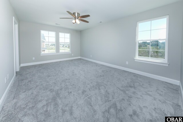 spare room featuring carpet, ceiling fan, visible vents, and baseboards