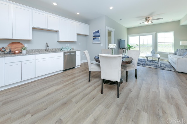 kitchen with light stone counters, white cabinetry, open floor plan, and stainless steel dishwasher