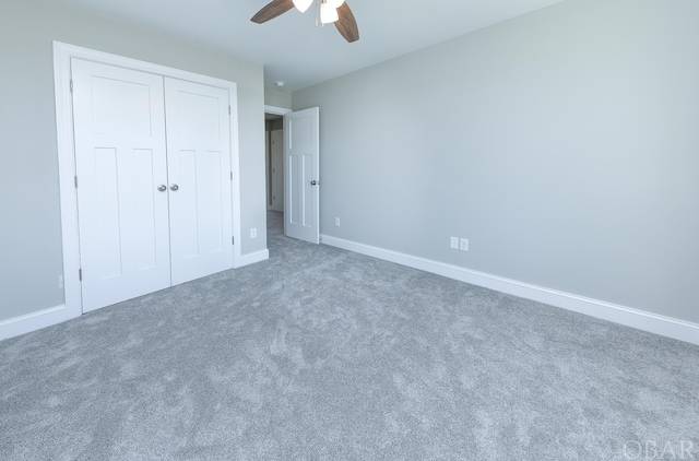 unfurnished bedroom featuring baseboards, dark colored carpet, and a closet