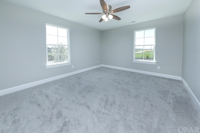 spare room featuring carpet flooring, ceiling fan, visible vents, and baseboards