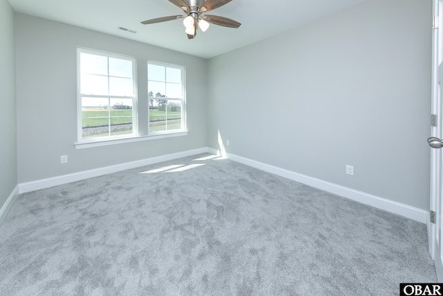 carpeted empty room with visible vents, baseboards, and a ceiling fan