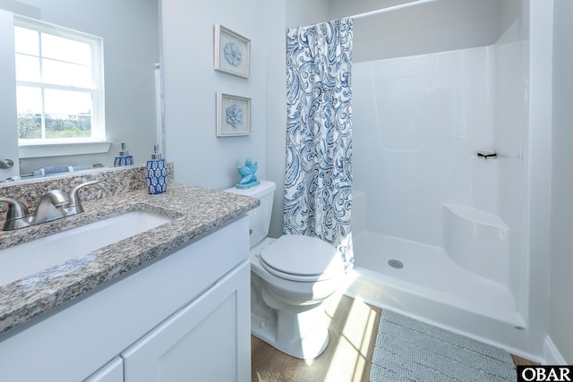 bathroom with a stall shower, vanity, and toilet