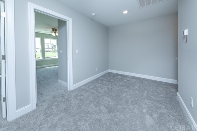 empty room featuring baseboards, visible vents, dark colored carpet, and a ceiling fan