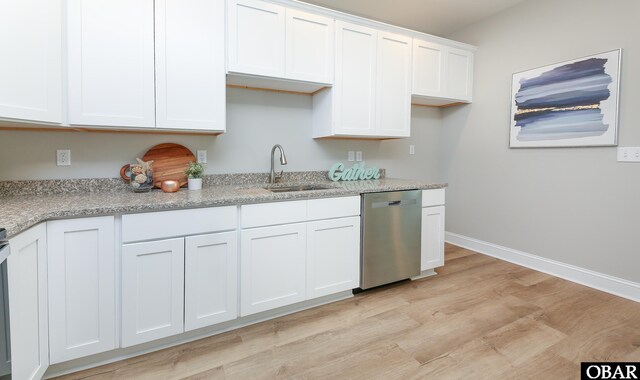 kitchen featuring light stone counters, a sink, light wood-style floors, white cabinets, and dishwasher