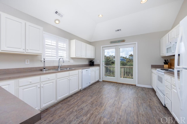 kitchen featuring white appliances, visible vents, white cabinets, lofted ceiling, and a sink