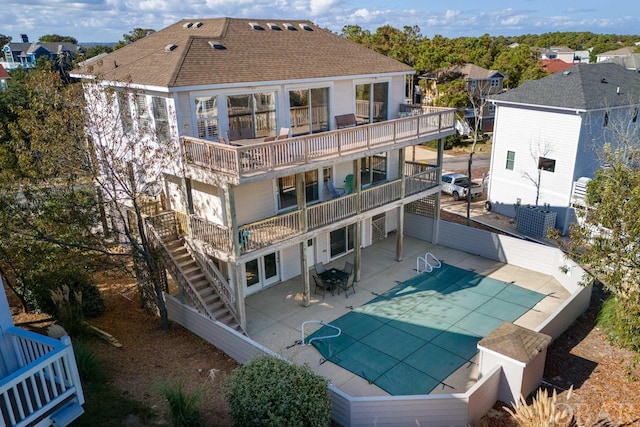 rear view of property featuring a patio, a balcony, stairs, driveway, and roof with shingles