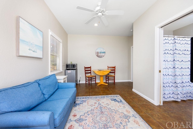 living room with dark tile patterned floors, baseboards, and a ceiling fan