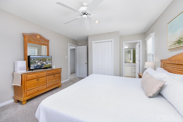 bedroom featuring baseboards, light colored carpet, ceiling fan, ensuite bathroom, and a closet