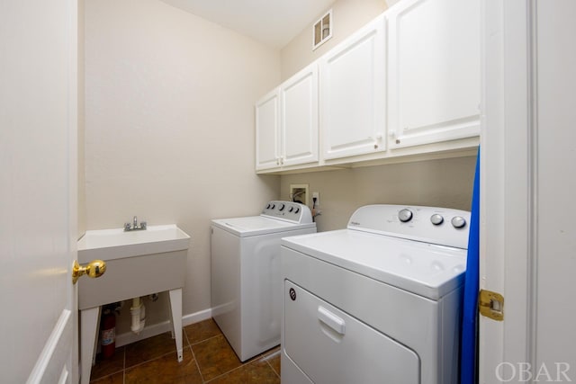 laundry area with dark tile patterned flooring, visible vents, baseboards, independent washer and dryer, and cabinet space