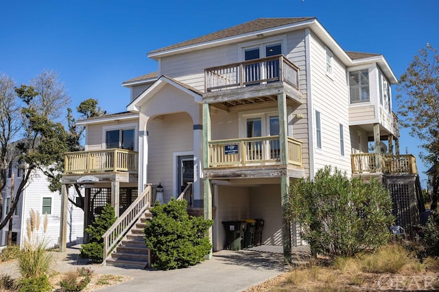 view of front of property with a balcony, a carport, stairs, and concrete driveway