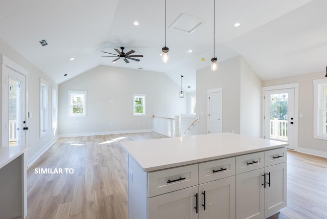 kitchen with open floor plan, light countertops, hanging light fixtures, and white cabinetry