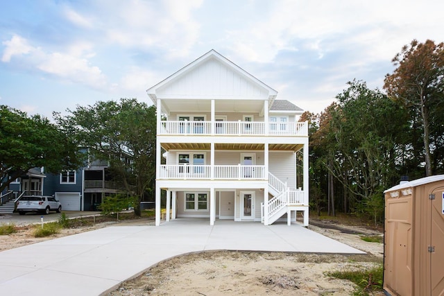 raised beach house featuring board and batten siding, covered porch, and a balcony