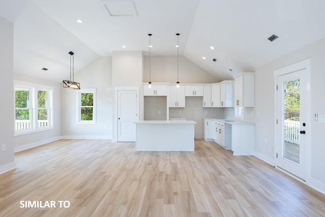 kitchen with light wood-style flooring, a center island, light countertops, white cabinetry, and pendant lighting