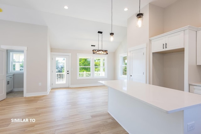 kitchen featuring light countertops, light wood finished floors, white cabinetry, and decorative light fixtures