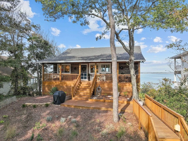 view of front of property featuring covered porch, roof with shingles, a water view, and stairs