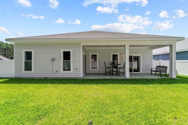 back of property featuring a shingled roof, fence, a lawn, and a patio