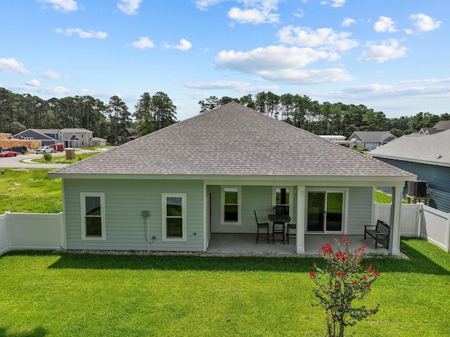 rear view of house featuring a shingled roof, a yard, a patio, and central AC unit