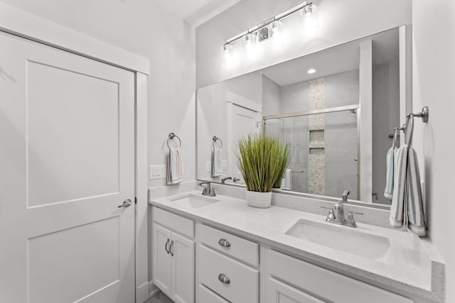 bathroom featuring double vanity, a tile shower, and a sink